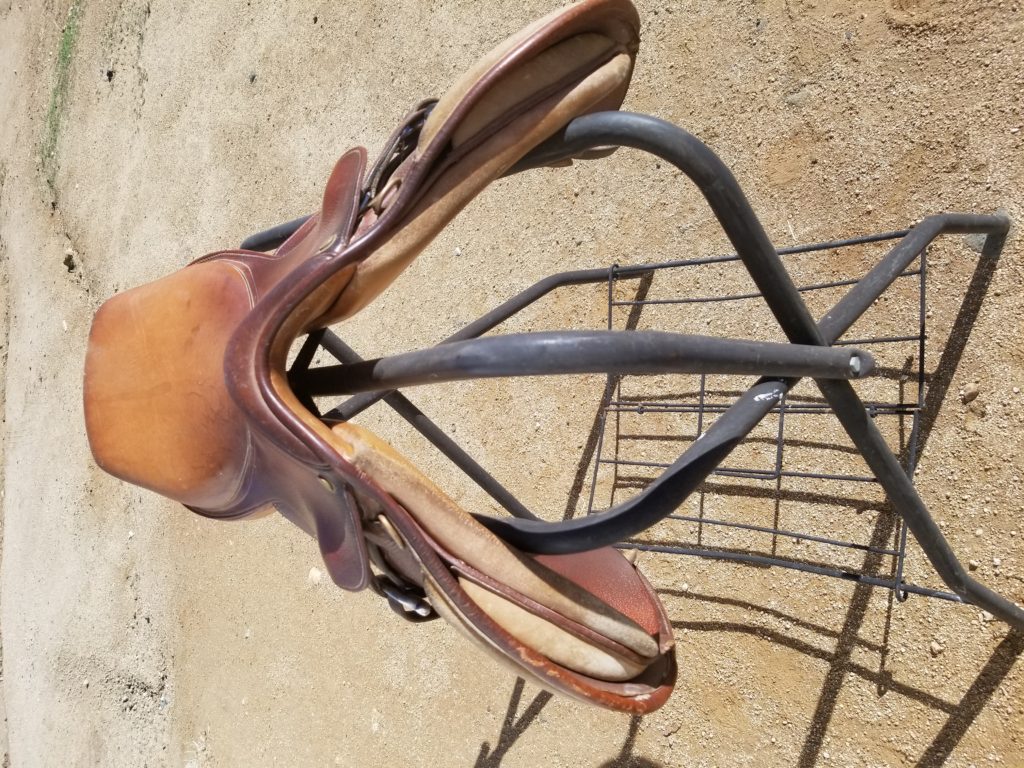 A saddle sitting on top of a metal stand.