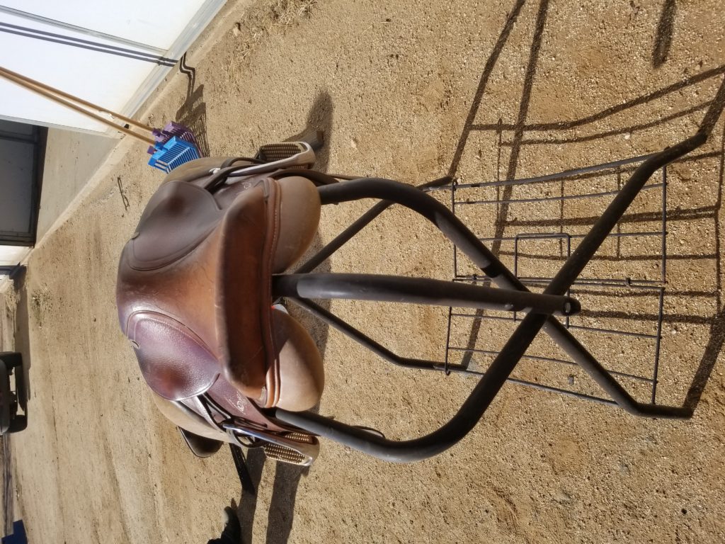 A saddle sitting on top of a metal stand.
