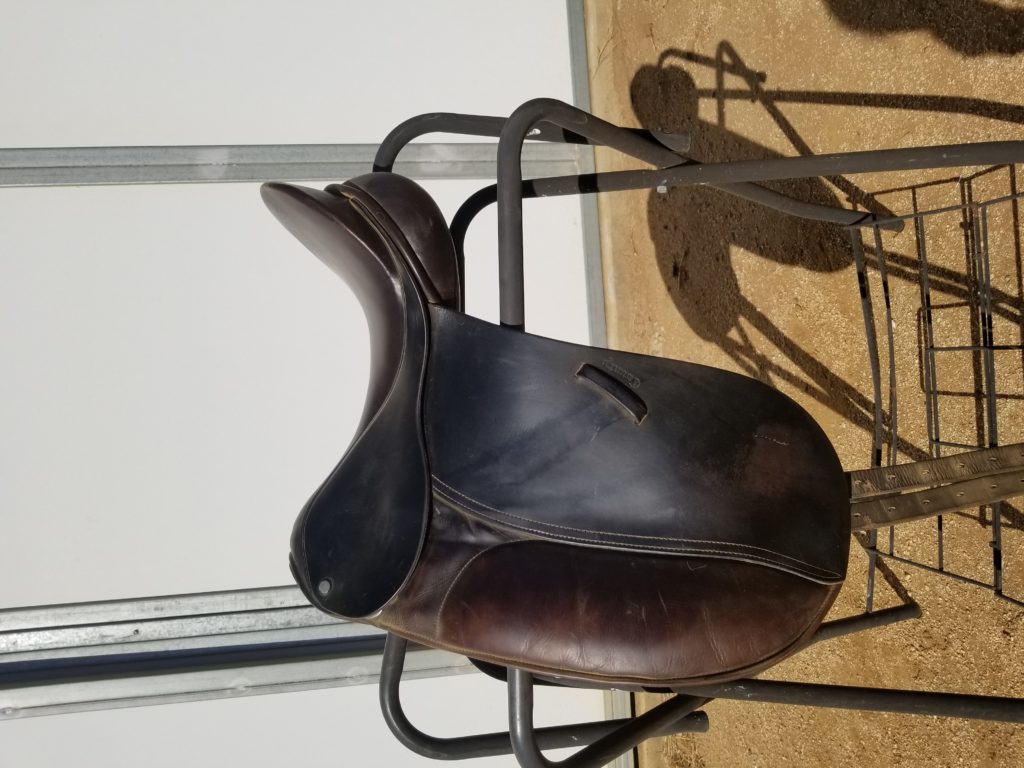 A brown saddle sitting on top of a metal stand.